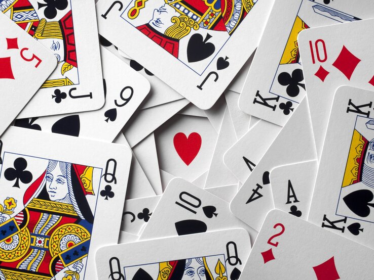 Ein Durcheinander von Spielkarten zeigt verschiedene Farben und Werte, mit einem roten Herz in der Mitte.