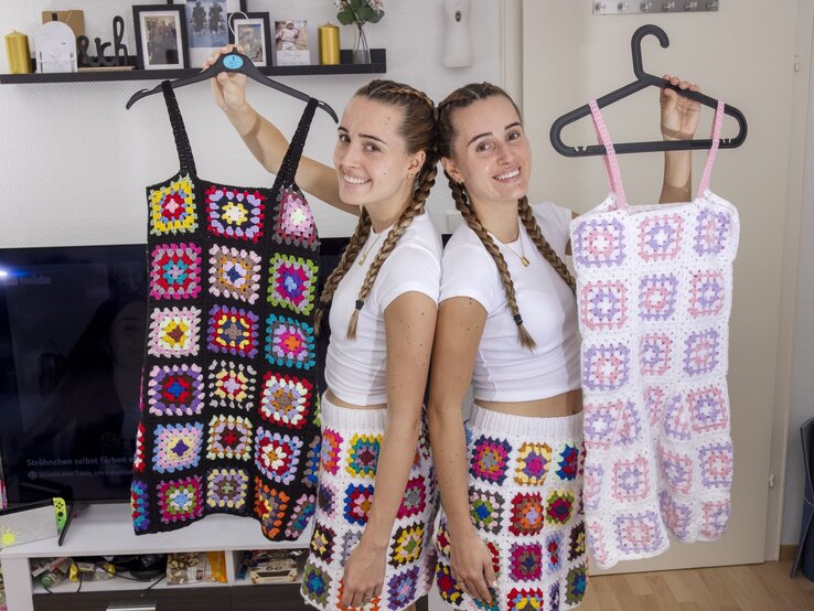 Die Lesotwins Leonie und Sophie zeigen selbst gehäkelte Röcke und Kleider und lachen dabei in die Kamera.