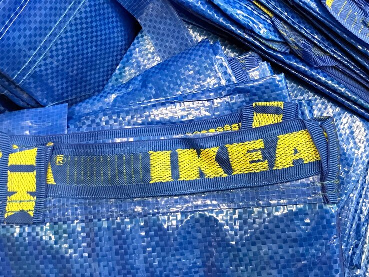 Blaue Einkaufstaschen aus Kunststoff mit gelbem "IKEA"-Logo liegen gestapelt aufeinander.