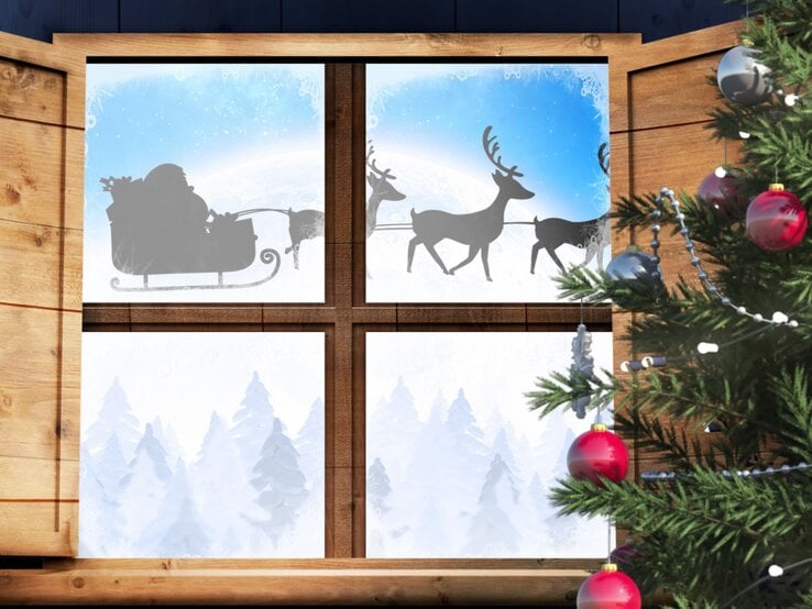 Ein Holzfenster mit einem weihnachtlichen Fensterbild, das eine winterliche Landschaft mit schneebedeckten Tannen und einem vorbeiziehendem Rentierschlitten zeigt.