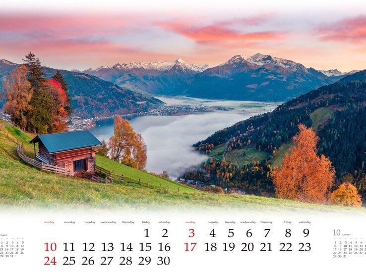 Ein Kalenderblatt, das eine kleine Holzhütte auf einer grünen Bergwiese zeigt, umgeben von Herbstbäumen, mit Blick auf einen nebelverhangenen See und schneebedeckte Berge im Morgenrot.