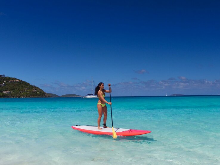 Eine Frau paddelt in der Karibik auf einem SUP, Stand Up Paddle Board.