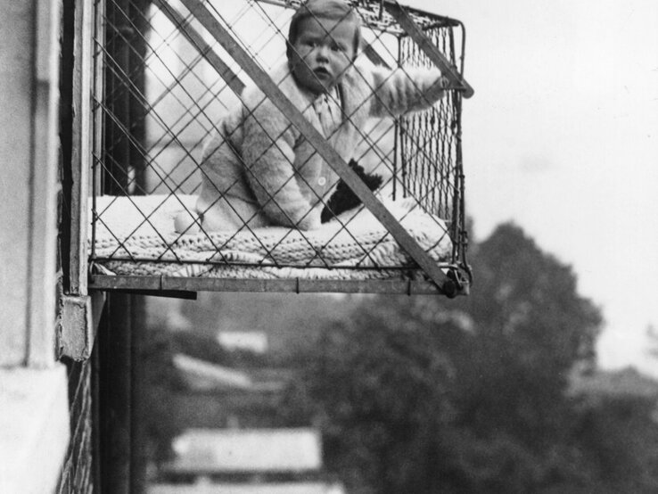 Baby in einem Käfig am Fenster zur damaligen Zeit. | © Getty Images/Fox Photos