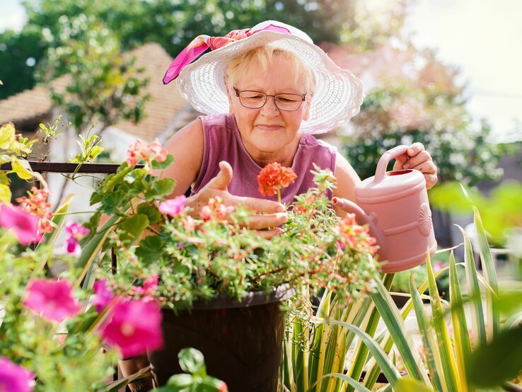 Frau kontrolliert ihre Blumen im Garten