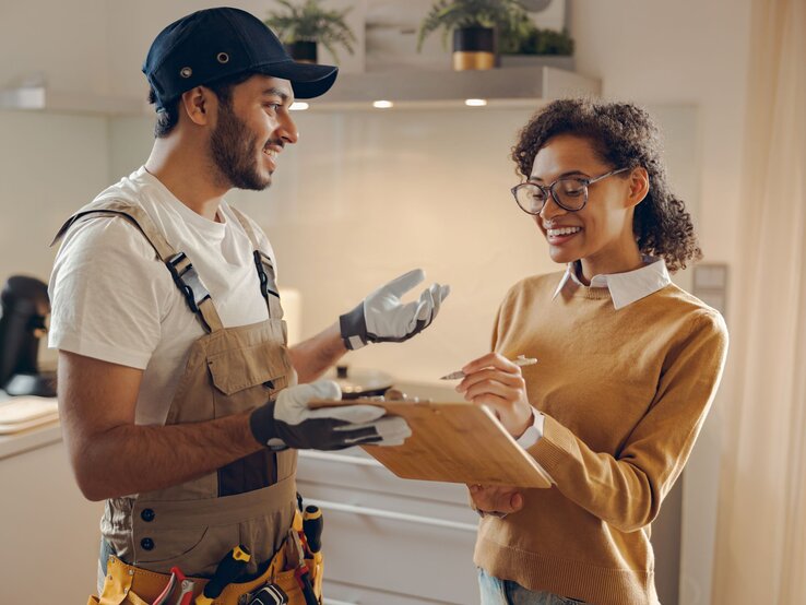 Zu sehen ist eine Frau, die sich mit einem Handwerker unterhält