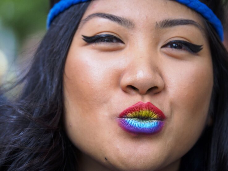 Nahaufnahme einer Frau mit blauer Mütze, buntem Regenbogen-Lippenstift und dramatischem schwarzen Eyeliner. | © Getty Images/ Merrill Images