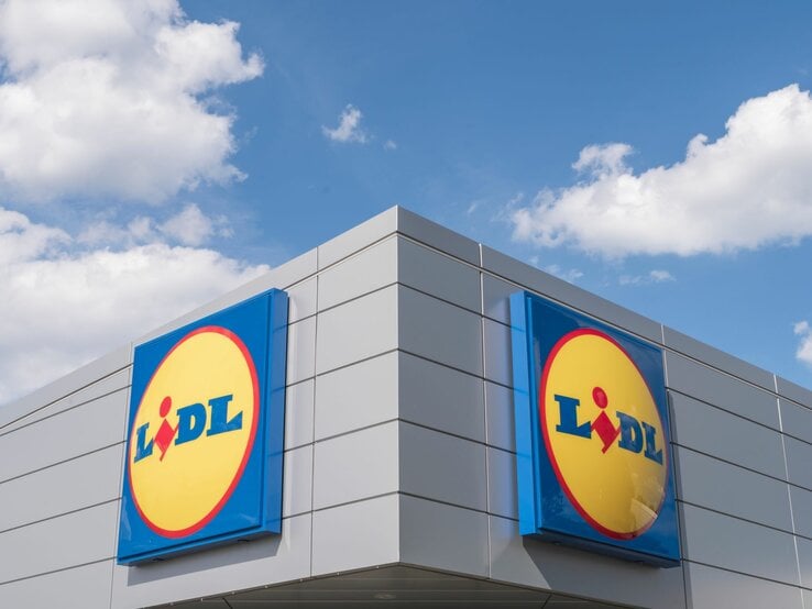 Moderne Fassade eines Lidl-Supermarkts mit markantem Logo vor blauem Himmel und vereinzelten Wolken.