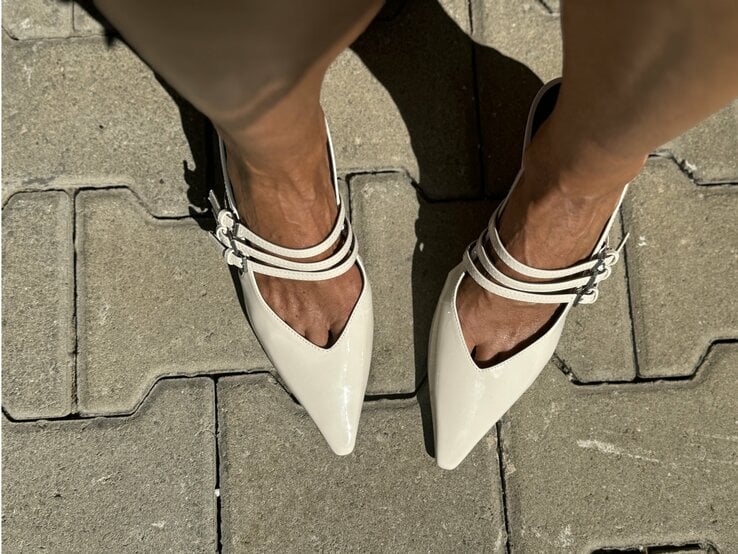 Beine, die in beige Sling-Pumps stecken. Diese Schuhe haben spitze Kappen und mehrere dünne Riemen mit Schnallen, die über den Spann verlaufen. | © Renate Zott