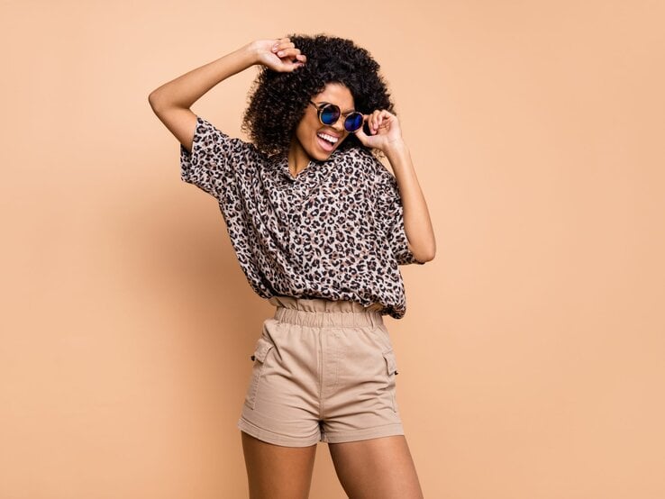 Zu sehen ist eine hüsche Frau, die, passend zum Sommer, ein Leopardenshirt und eine Shorts trägt.