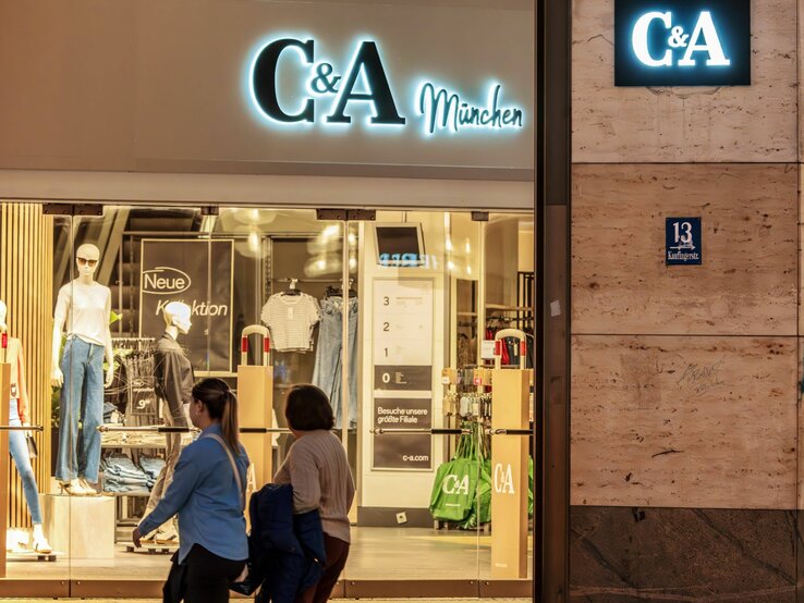 C&A-Filiale in München bei Nacht, mit Schaufensterpuppen und Passanten.
