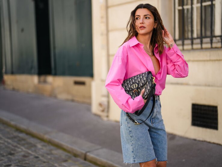 Zu sehen ist eine blonde Frau mit pinker Bluse und Jeans Bermudas.