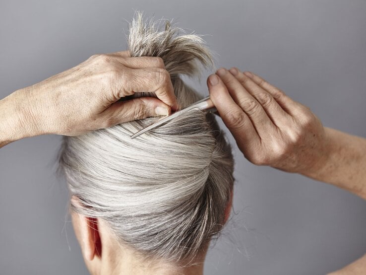 Zu sehen ist eine Frau mit grauen Haaren, die einen French Twist trägt