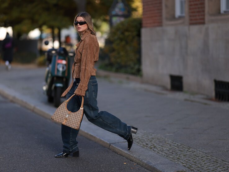 Streetstylebild von Frau mit dunkler Jeans und brauner Jacke.