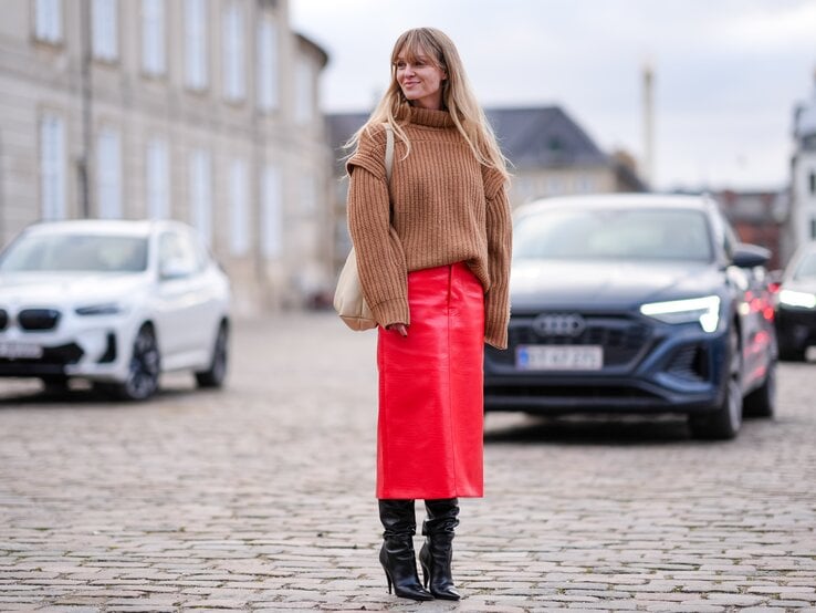 Streetstylefoto von Frau in rotem Lederrock. Zusätzlich trägt sie einen hellen Strickpullover mit Rollkragen