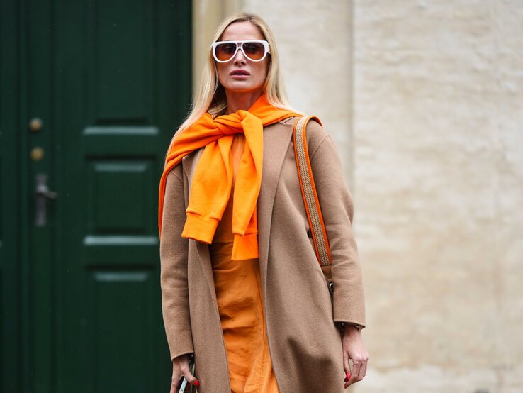 Zu sehen ist eine Frau in einem stylischen Streetstyle Outfit mit hohem Orangeanteil