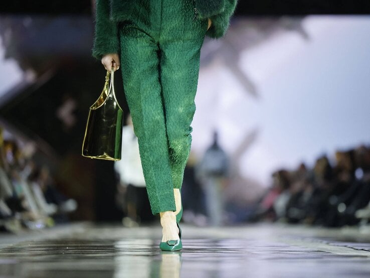 Nahaufnahme eines Models auf dem Laufsteg mit grüner Stoffhose, passendem Oberteil und eleganten grünen Schuhen mit Tasche. | © IMAGO / APress International