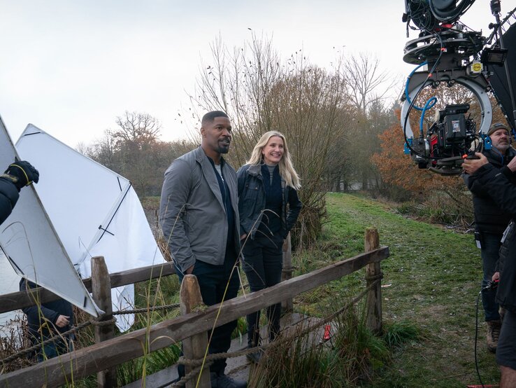 Drehszene mit Jamie Foxx und Cameron Diaz in Herbstlandschaft, umgeben von Kameras, Reflektoren und technischem Equipment. | © John Wilson/Netflix