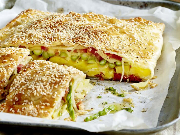 Käse-Tomaten-Tarte auf einem silbernen Blech mit weißem Backpapier.