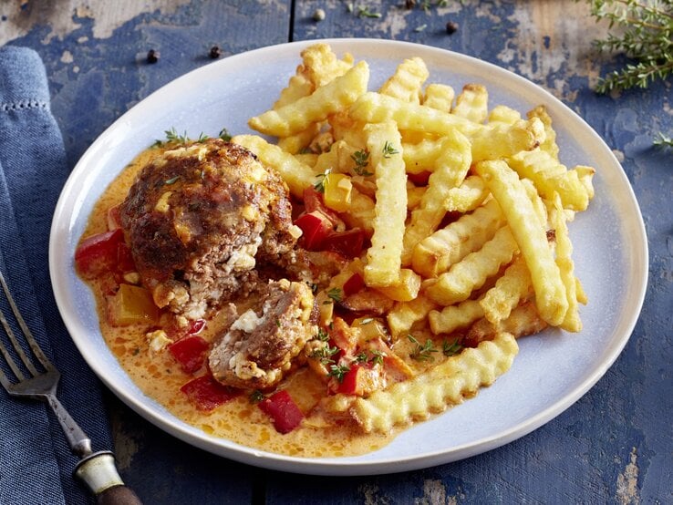 Mini-Braten in Paprika-Rahm auf einem weißen Teller auf dunkelblauem Hintergrund.