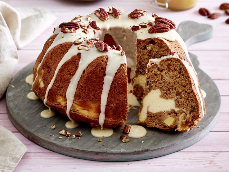 Apfel-Gugel mit Cheesecake-Füllung auf einem grauen Tortenteller auf rosa Hintergrund.