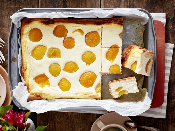 Aprikosen-Käsekuchen in einem Backblech auf hölzernem Hintergrund. 