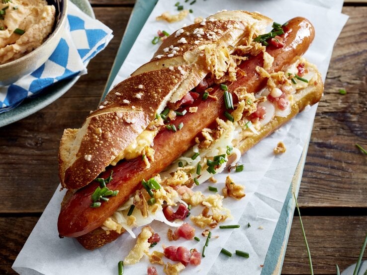 Hotdog auf bayerische Art auf weißem Papier auf hölzernem Hintergrund. 