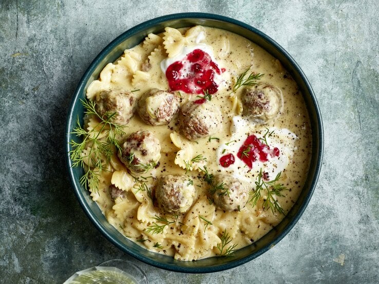 One-Pot-Pasta Köttbullarstyle in einer dunkelblauen Schüssel auf grauem Hintergrund.