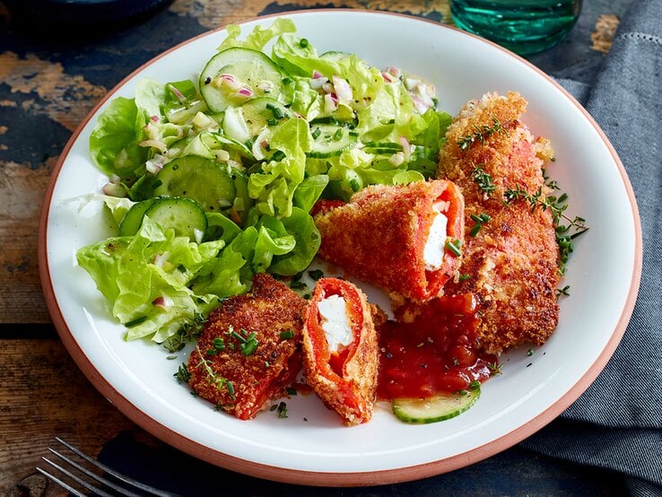 Feta-Paprika-Cordon-bleu auf einem weißen Teller auf hölzernem Hintergrund.