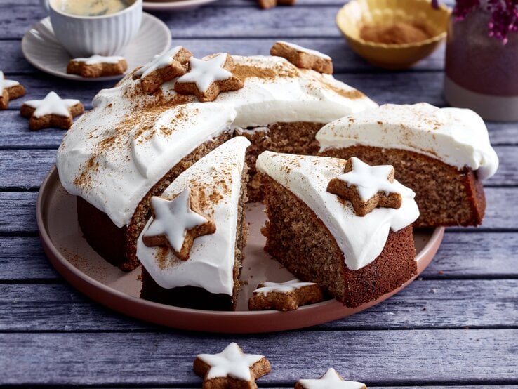 Zimtstern-Nusskuchen auf einem braunen Teller auf grauem Hintergrund. Links hinten auf dem Foto eine Tasse Kaffee.