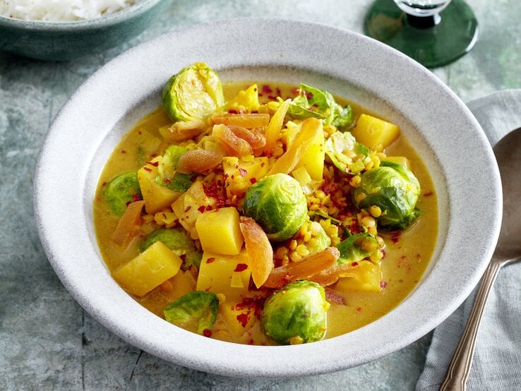 Rosenkohl-Steckrüben-Curry in einer weißen Schüssel auf grauem Hintergrund.