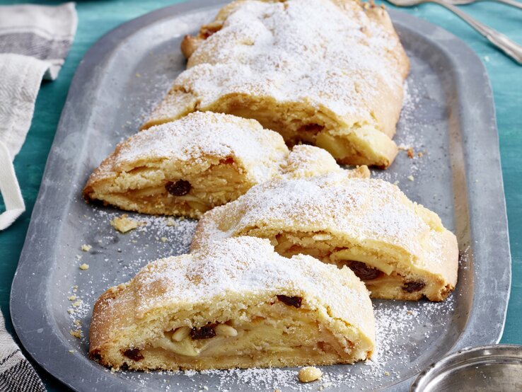 Südtiroler Apfelstrudel auf einem silbernen Servierteller auf blauem Hintergrund. 