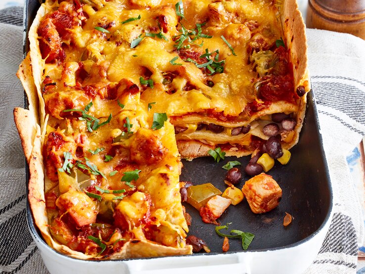 Tortilla-Hähnchen-Lasagne in einer Auflaufform auf einem Geschirrtuch.